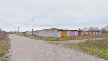 Rows of old worn garageboxes with colorful doors along a dirtroad in Paldiski, Estonia 