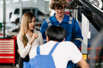 Asian woman customer looking the engine while Auto Mechanic communicate and showing the point at vehicle part for repair, Car service and maintenance Concept