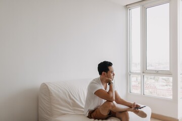 Bored and lonely asian man with his spare time to waste in his apartment.