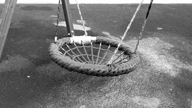 Swinging empty swings. Monochrome video.