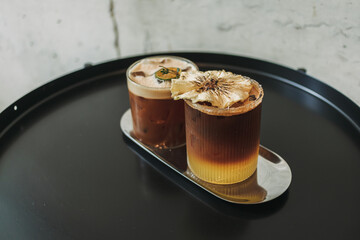 Two iced yusu orange coffee special drinks served on black table in the cafe.