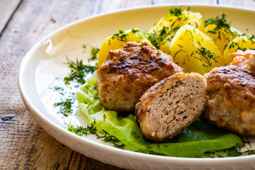 Fried meatballs with boiled potatoes and carrot salad on wooden table
