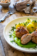 Fried meatballs with boiled potatoes and carrot salad on wooden table
