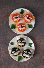 Tartlets Kittens with cheese, egg and caviar on two round plates on brown background, Top view