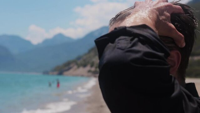 Attractive man combs wet hair back by the sea