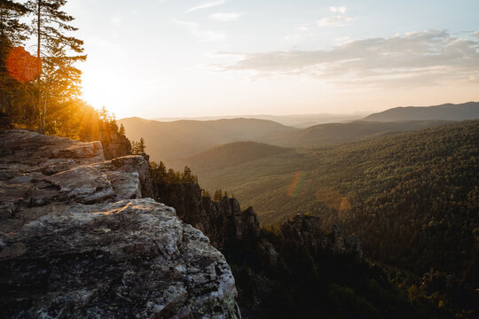 The evening sunset sun shines behind the mountain, the glare of the sun of beautiful color, the mountain landscape of the ridge of the southern Urals russia, the panorama at the top of the cliff.