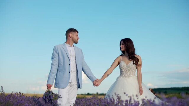 newlyweds in love hold hands in a lavender field