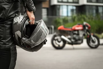 Foto op Plexiglas Biker walks to motorcycle holding helmet in hand © uladzislaulineu