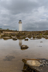 the historic Southerness Lighthouse in Scotland with reflections in tidal pools in the foreground