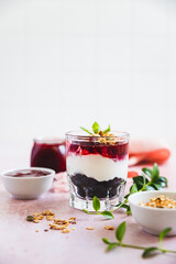 Cherry, cream cheese and chocolate biscuit portion layered dessert in glass, light pink background. Black forest trifle. No bake dessert.