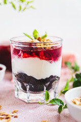 Cherry, cream cheese and chocolate biscuit portion layered dessert in glass, light pink background. Black forest trifle. No bake dessert.