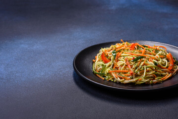 Fresh salad of sliced thin strips of carrot and zucchini on a concrete background