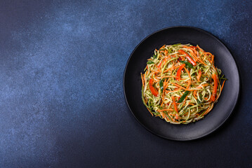 Fresh salad of sliced thin strips of carrot and zucchini on a concrete background