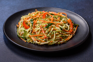 Fresh salad of sliced thin strips of carrot and zucchini on a concrete background