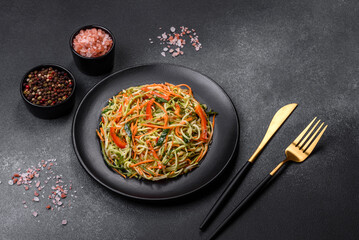 Fresh salad of sliced thin strips of carrot and zucchini on a concrete background