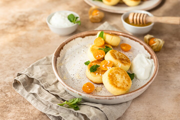 Curd or ricotta fritters with physalis, honey, yogurt and mint on ceramic plate. Cottage cheese pancakes, syrniki. Healthy and tasty breakfast.