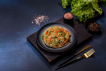 Fresh salad of sliced thin strips of carrot and zucchini on a concrete background