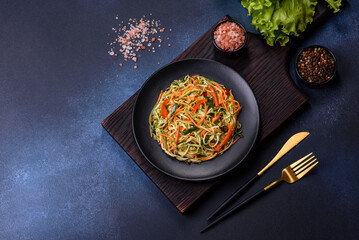 Fresh salad of sliced thin strips of carrot and zucchini on a concrete background