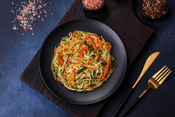 Fresh salad of sliced thin strips of carrot and zucchini on a concrete background