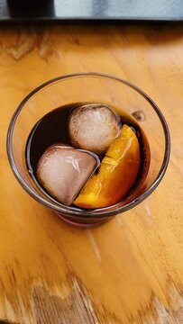 Glass of dark spanish vermouth with ice and an orange slice