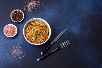 Fresh salad of sliced thin strips of carrot and zucchini on a concrete background