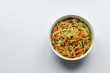 Fresh salad of sliced thin strips of carrot and zucchini on a concrete background