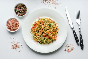 Fresh salad of sliced thin strips of carrot and zucchini on a concrete background