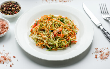 Fresh salad of sliced thin strips of carrot and zucchini on a concrete background
