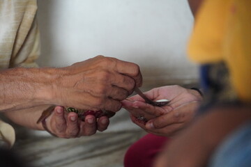 Pandit ji giving prasad in hand