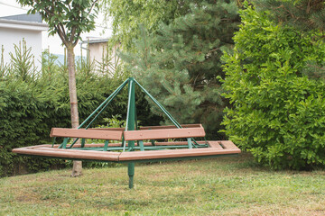 Obraz na płótnie Canvas Retro carousel for kids made of wood and iron. Children's roundabout placed home in the backyard. Surrounded by garden foliage. 