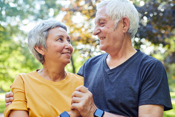 Optimistic attractive multiracial elderly 60s couple pose outdoors