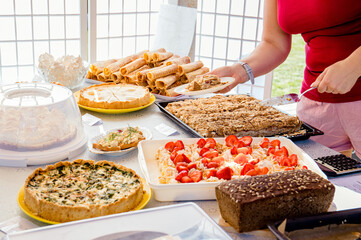 Close up view of person selling homemade pastry and cakes at home cafe day event. Person hands...