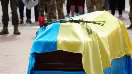 Unhappy woman with red roses and a coffin at a funeral. The funeral ceremony of a soldier. Funeral...