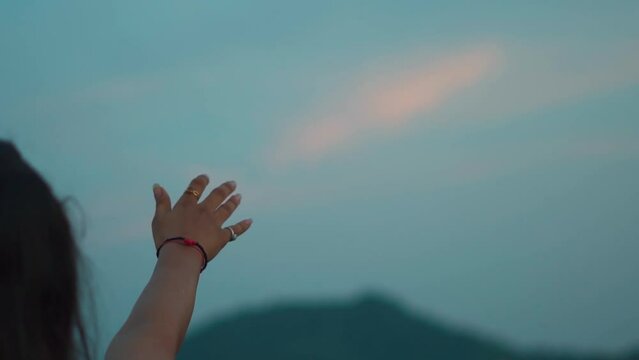 Close up shot of hand of a girl reaching out to the sky during sunset. Female extends her hand towards the sky in search of hope. Hopelessness in a woman. Looking for answers and reaching for sky.