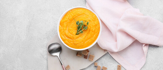 Bowl of tasty pumpkin cream soup on light background, top view