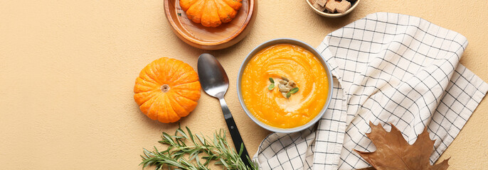 Bowl of tasty pumpkin cream soup on beige background, top view