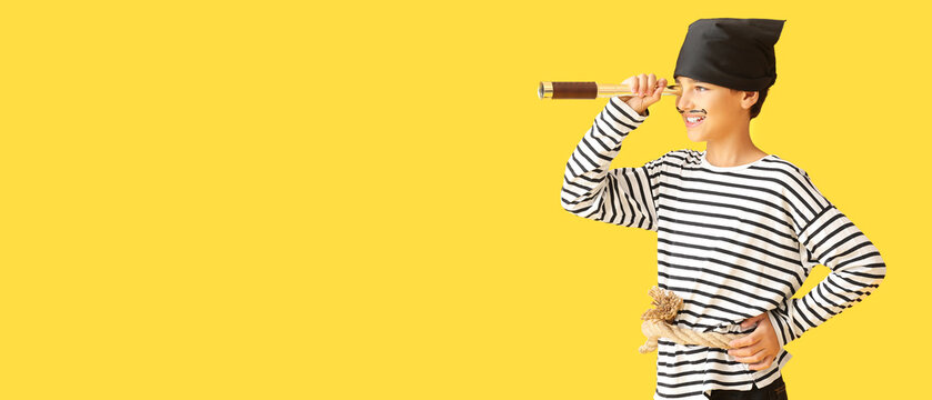 Little boy dressed as pirate with spyglass on yellow background with space for text