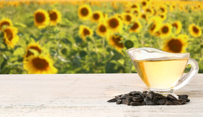 Gravy boat of oil and seeds on table in sunflower field