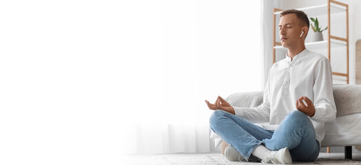 Young man meditating and listening to music at home. Banner for design