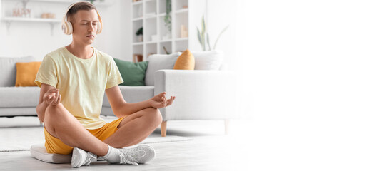 Young man meditating and listening to music at home. Banner for design