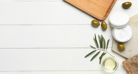 Cream, olives and oil on white wooden background with space for text, top view