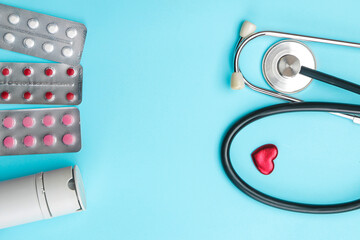 Various pills and a stethoscope on a blue background. top view and free space. cardiology and heart health.