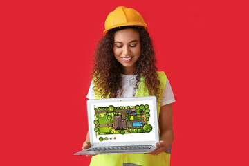 African-American female landscape designer with laptop on red background