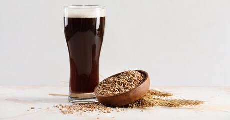 Glass of fresh dark beer on light background