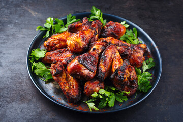 Traditional barbecue chicken wings and drumsticks with hot chili and coriander served as close-up on a rustic plate