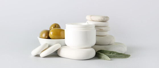 Jar of cream with olive oil extract and spa stones on light background