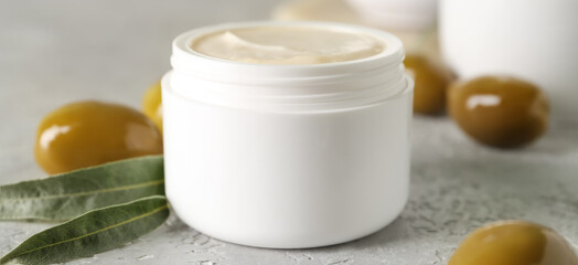 Jar of cream with olive oil extract on light background, closeup