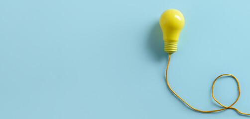 Yellow light bulb on blue background with space for text. Concept of idea