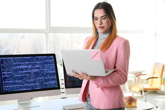 Transgender programmer with laptop working in office