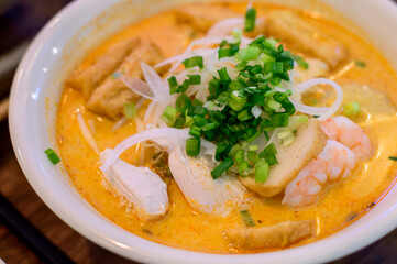 Top view of Vietnamese pho with prawns, chicken, tofu and spring onions on top.